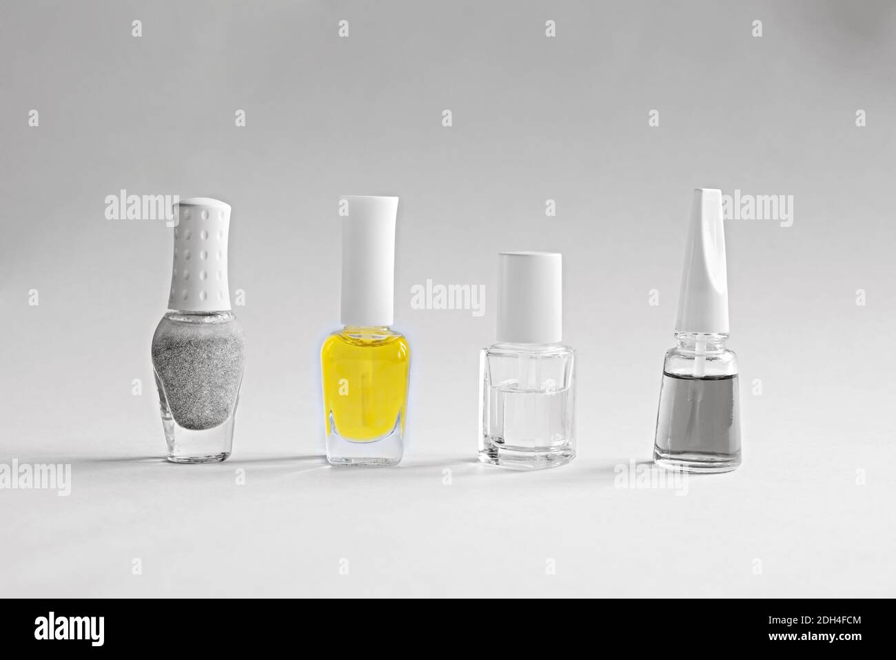 Una serie di prodotti per la cura delle unghie. Bottiglie con vernice per manicure grigia, trasparente e gialla. Colori dell'anno 2021. Foto Stock