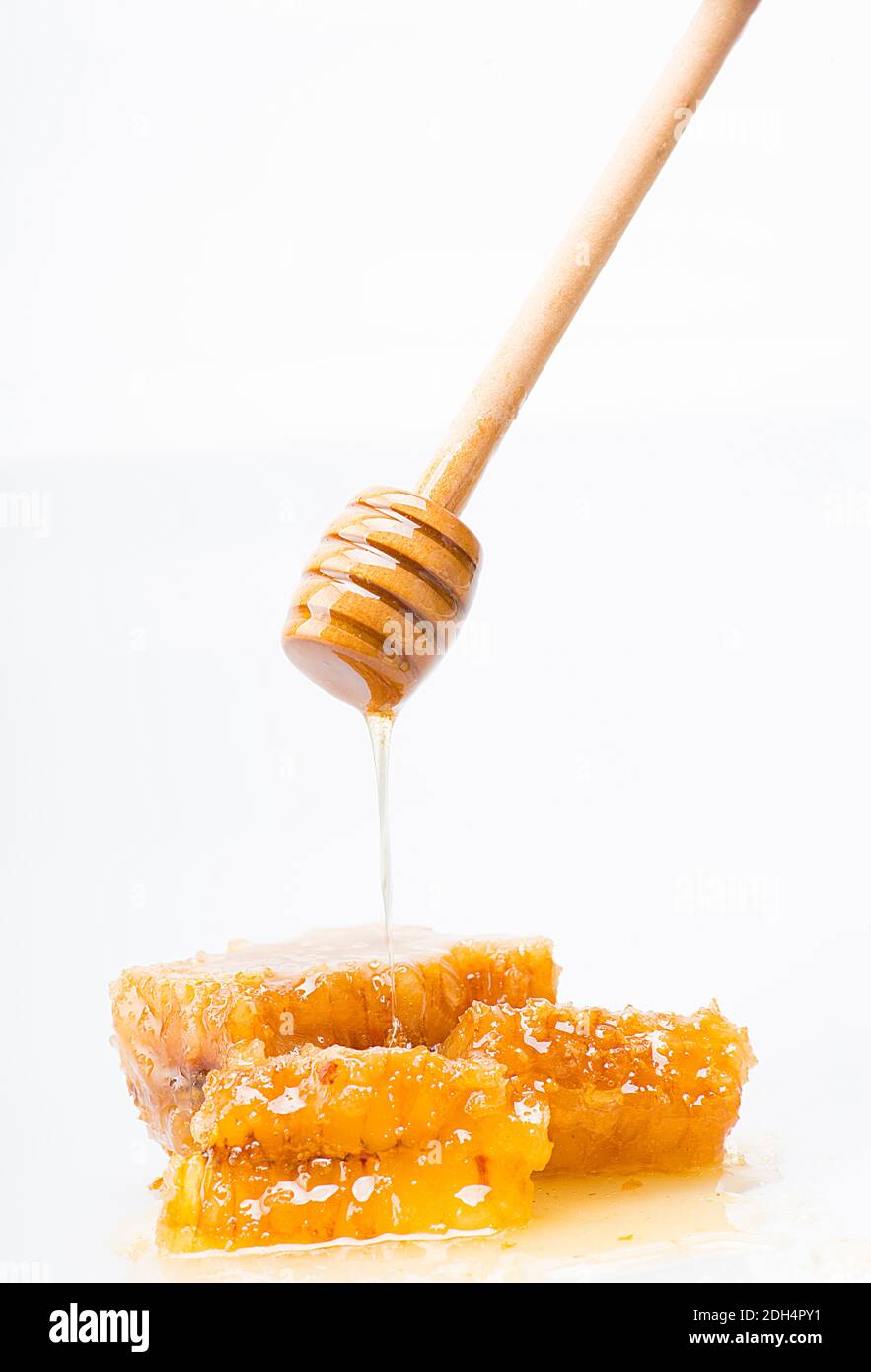 cucchiaio di miele speciale che gocciola il miele naturale su un nido d'ape Foto Stock