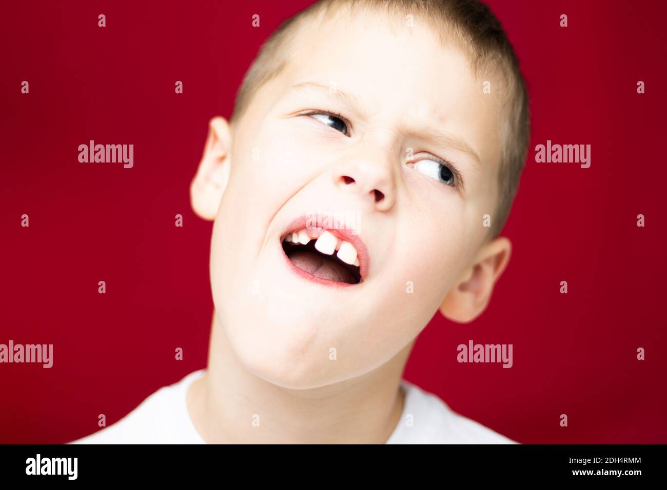 Ragazzo adolescente 7-10 mostra un posto da un dente perso su sfondo rosso Foto Stock