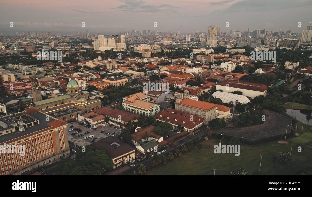 Edifici moderni, grattacieli sulla strada del traffico con auto aeree. Case e case del centro della città di Manila, Filippine, Asia. Paesaggio urbano cinematico della città tropicale della metropoli Foto Stock