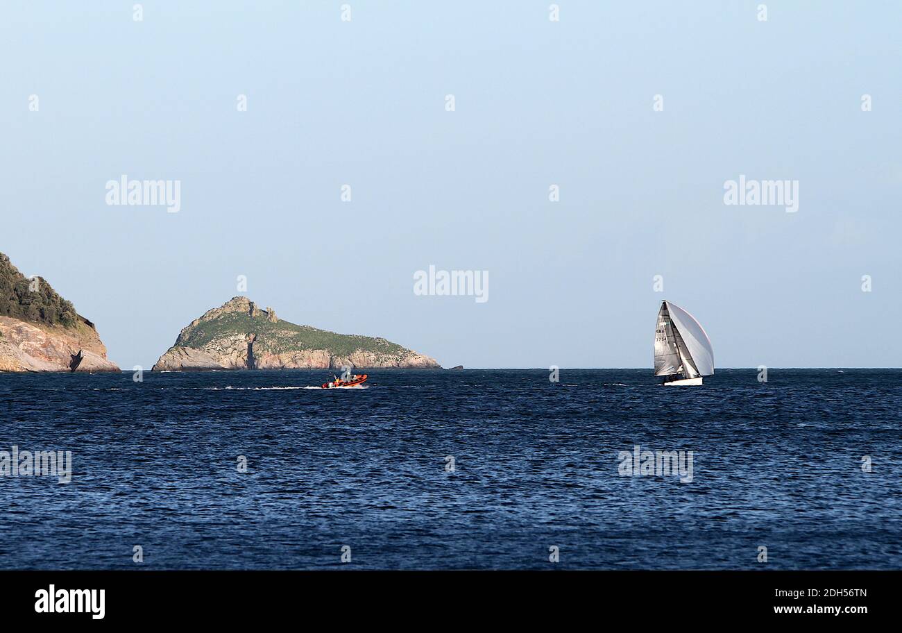 Thatcher Rock, Torbay, Devon: Uno yacht catturato alla luce del sole nel tardo pomeriggio. Thatcher Rock appare sullo sfondo di questa foto. Foto Stock