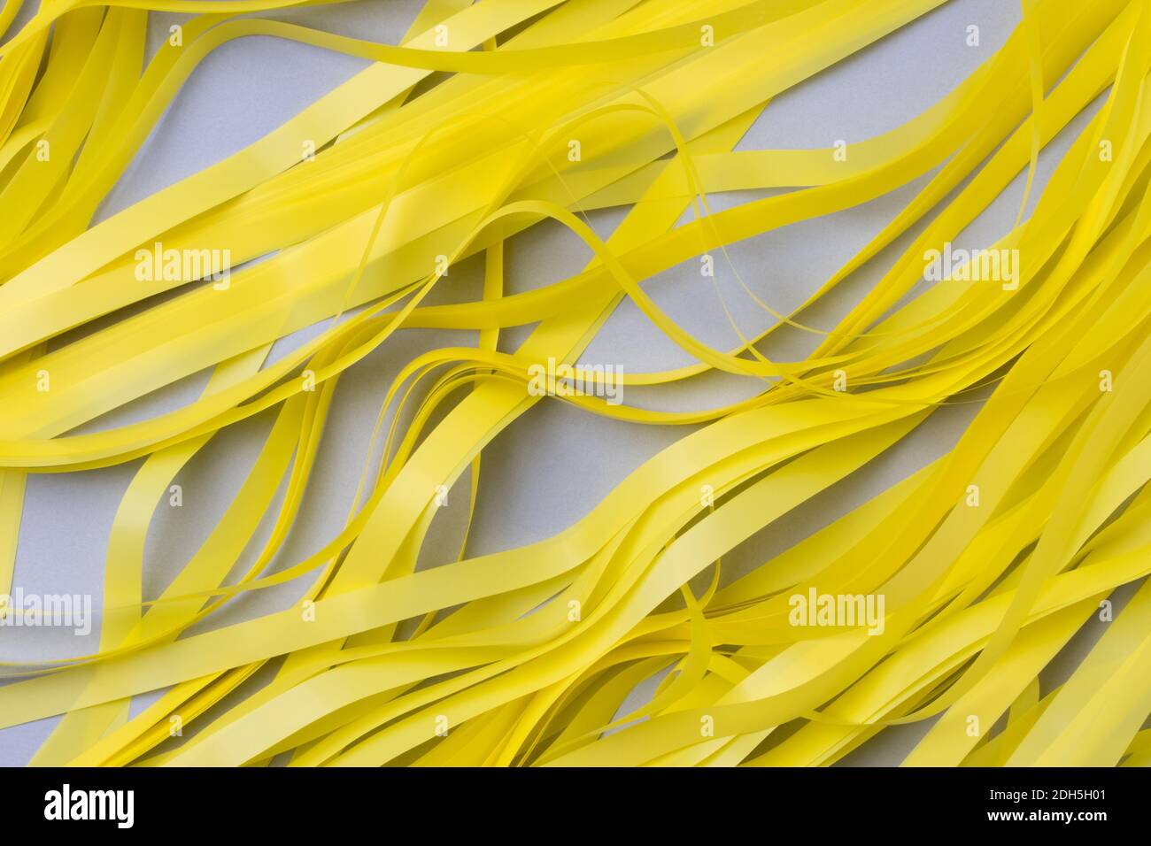 Sfondo grigio astratto con strisce di carta ondulata di colore giallo brillante. Foto Stock
