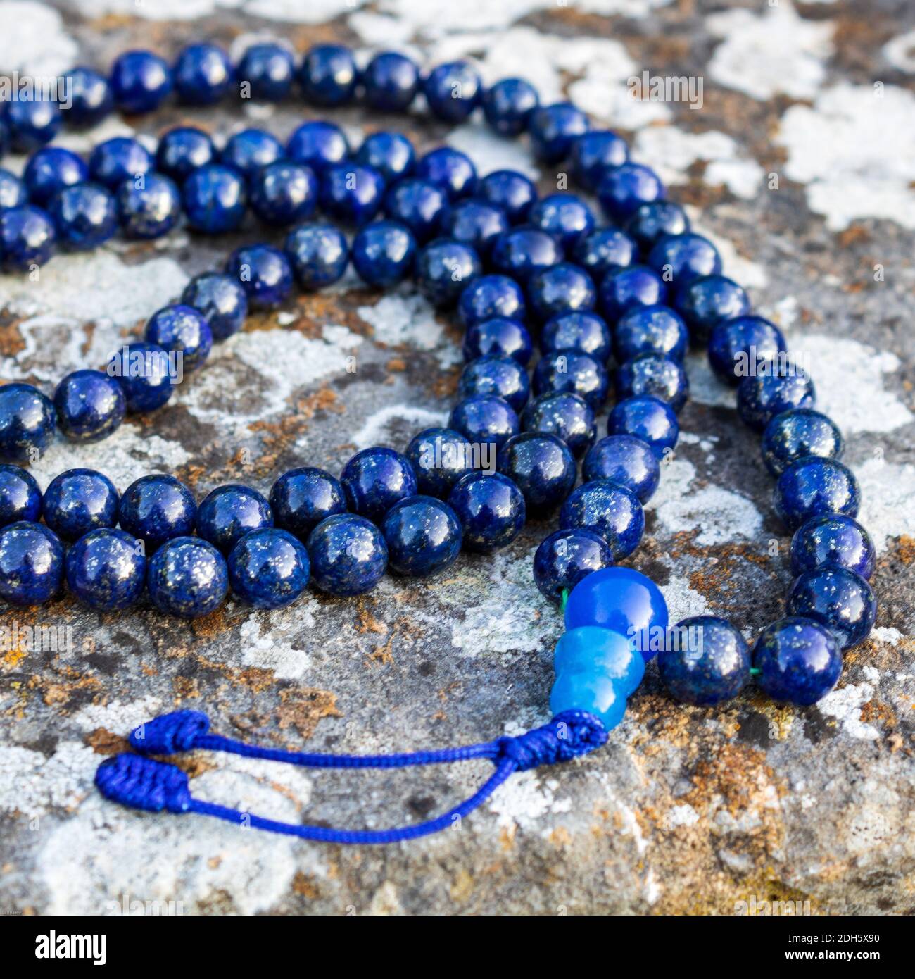 Un closeup di perle blu di mala (lapislazzuli) su pietra - accessorio yoga e meditazione Foto Stock