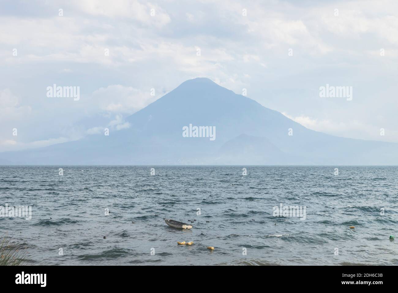 Piccola barca sul lago soleggiato Atitlan con vista sul vulcano a Panajachel, Guatemala Foto Stock