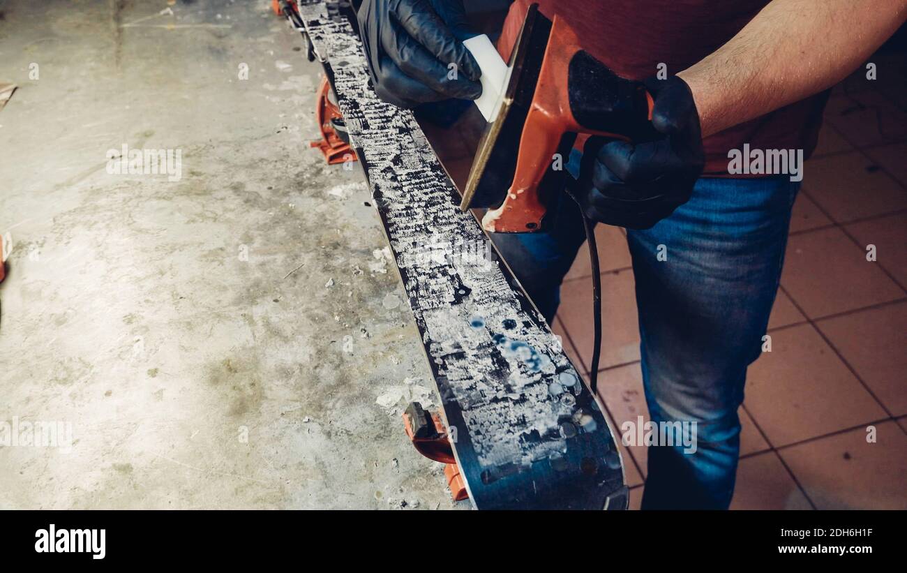 Applicazione di cera calda alla base da sci con il ferro da stiro. Applicazione della cera da sci alla base da sci. Sintonizzazione della base sci. Ferro da sci e barre di cera. Servizio sci AN Foto Stock