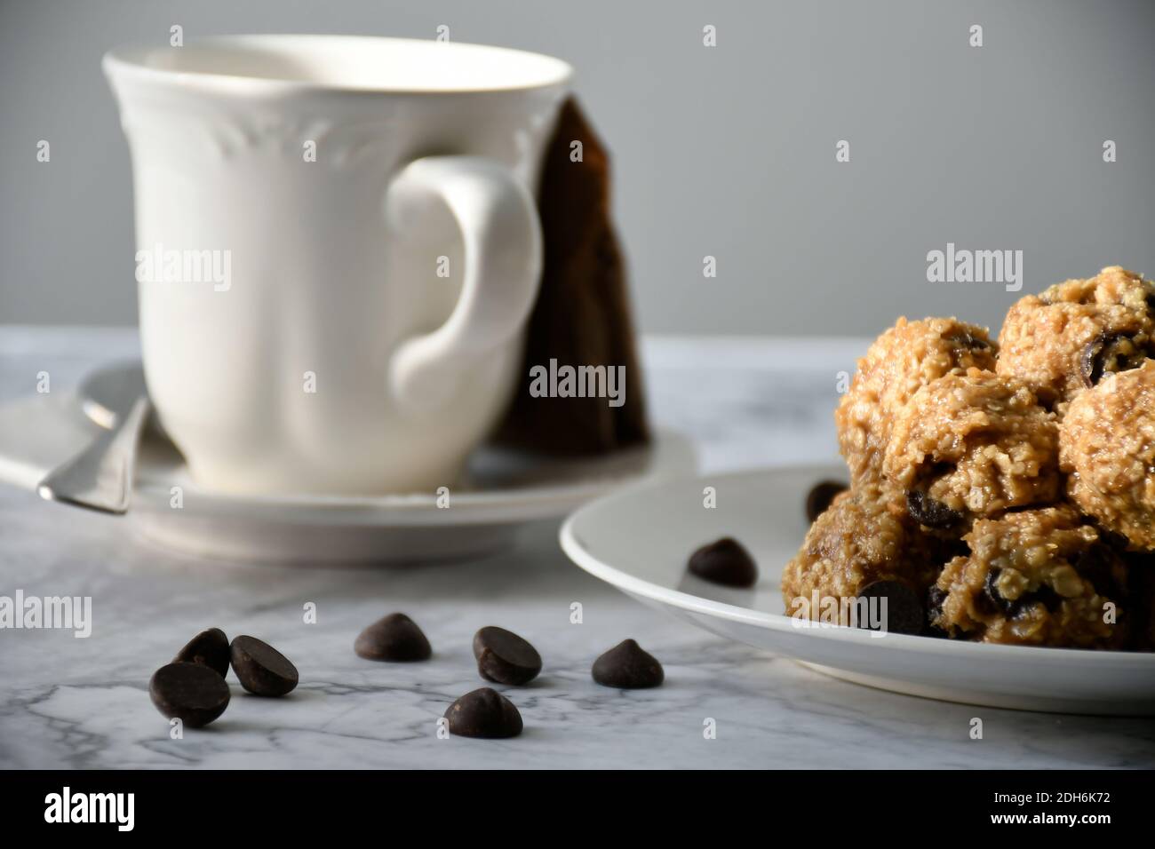 Cibo Fotografia di palline di farinata d'avena con gocce di cioccolato sul piatto con tazza da tè, vista del livello degli occhi Foto Stock