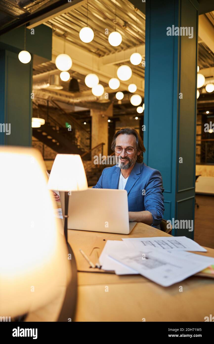 Signore Mirthful che usa il laptop per fare il lavoro a distanza Foto Stock