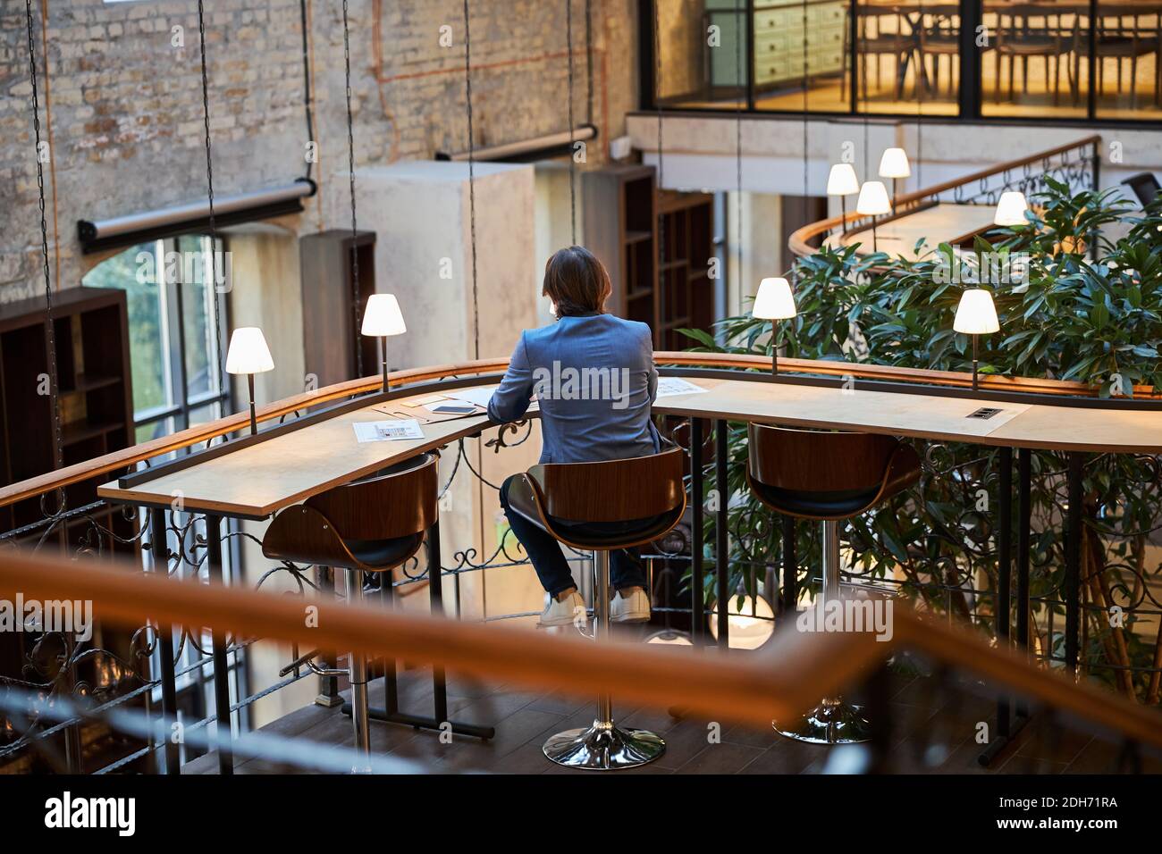 Uomo solitario seduto al tavolo nello spazioso salotto dell'hotel Foto Stock