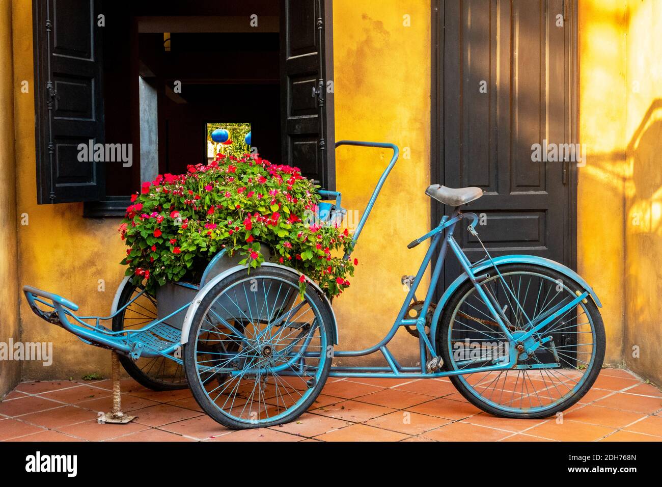 Bicicletta decorativa blu d'epoca decorata con vasi di fiori sul via della città Foto Stock
