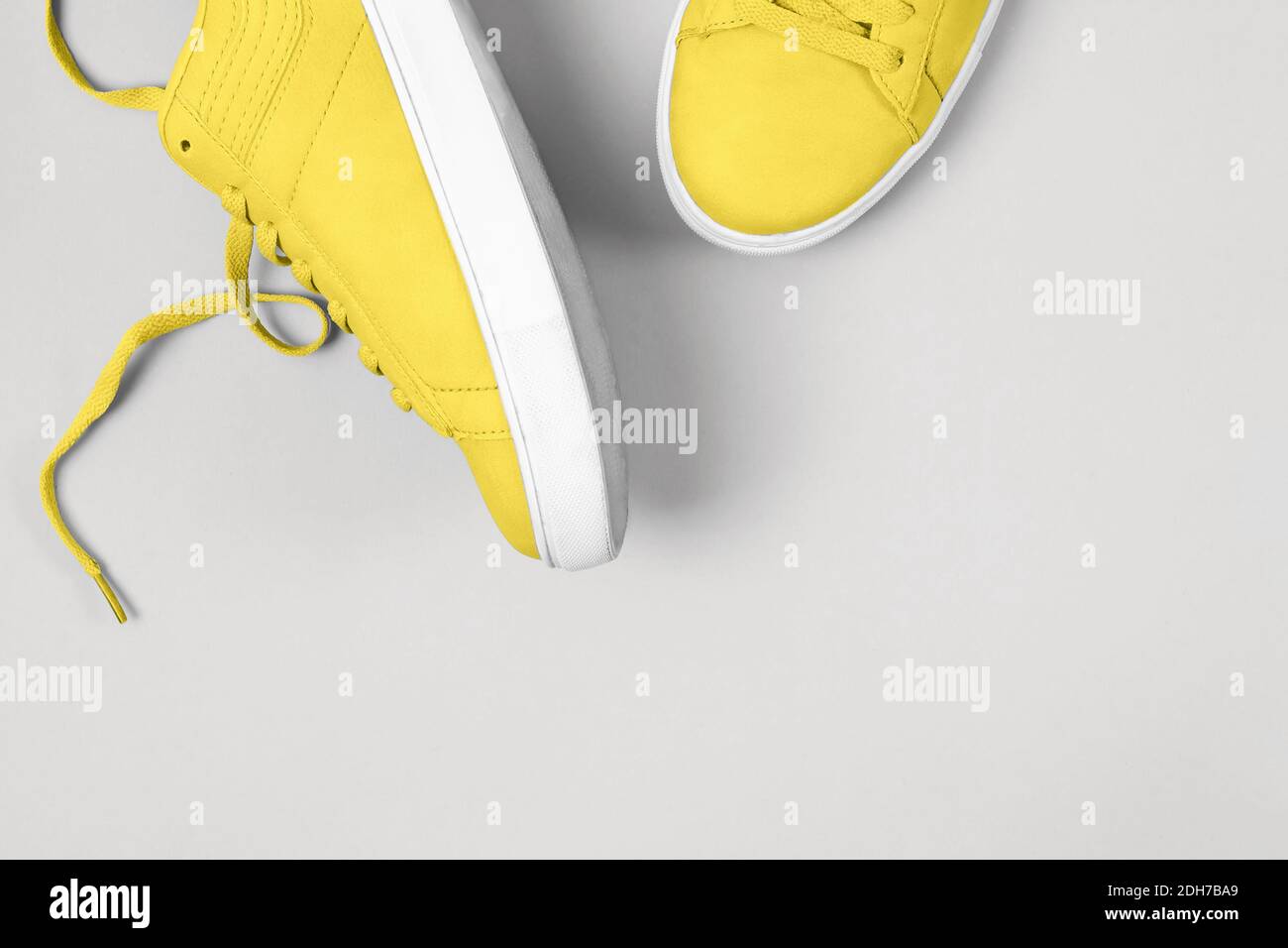 Sneaker gialle su sfondo grigio. Foto a colori, colori dell'anno 2021 illuminanti e Ultimate Grey. Foto Stock