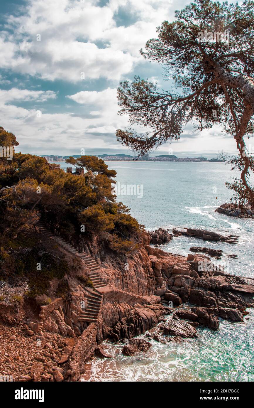 Vistas desde el camino de ronda de Sant Antoni de Calonge, mar en calma con unas scaleras para bajar a una cala Foto Stock