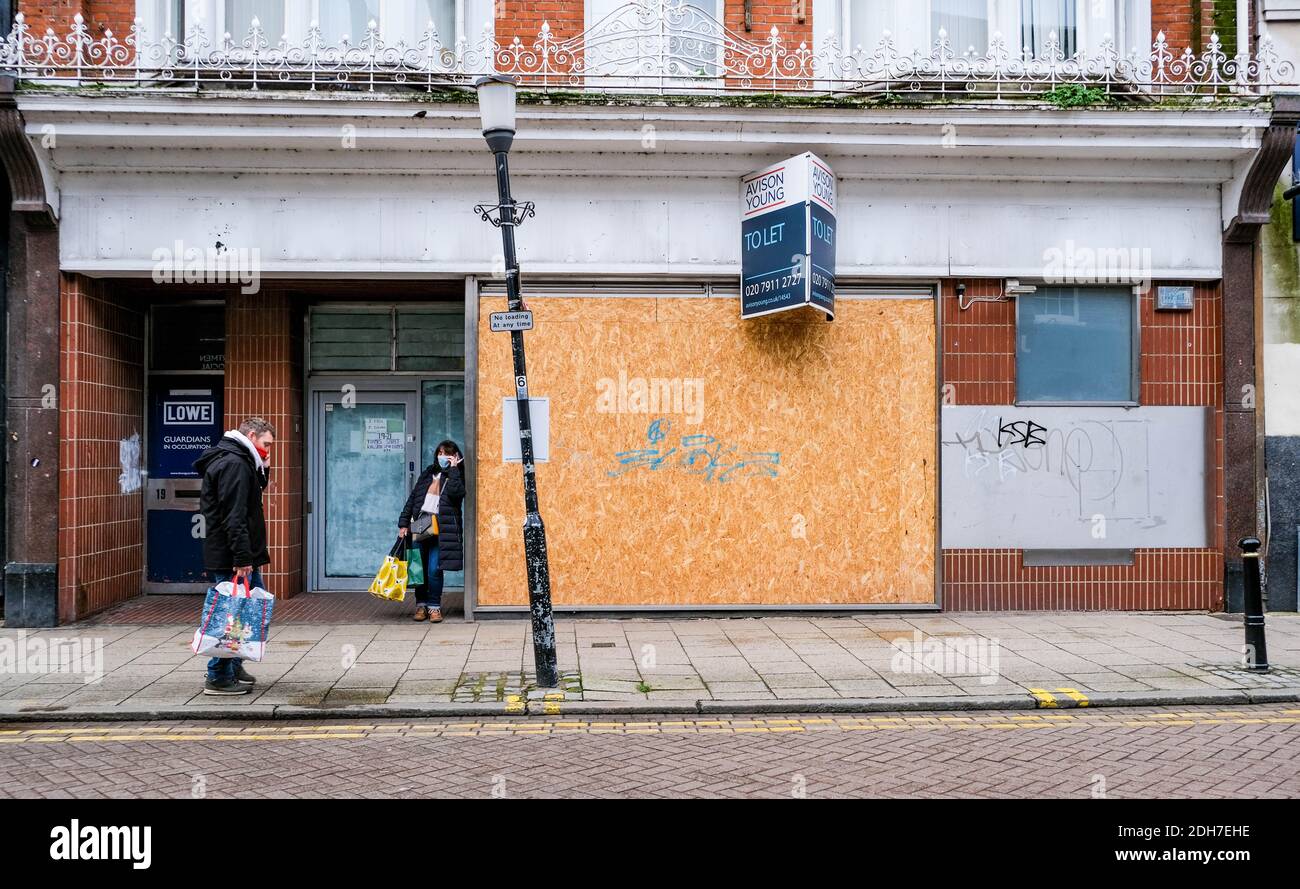 Kingston London, dicembre 09 2020, due persone che usano telefoni cellulari all'esterno DI un negozio di High Street chiuso durante il COVID-19 Foto Stock