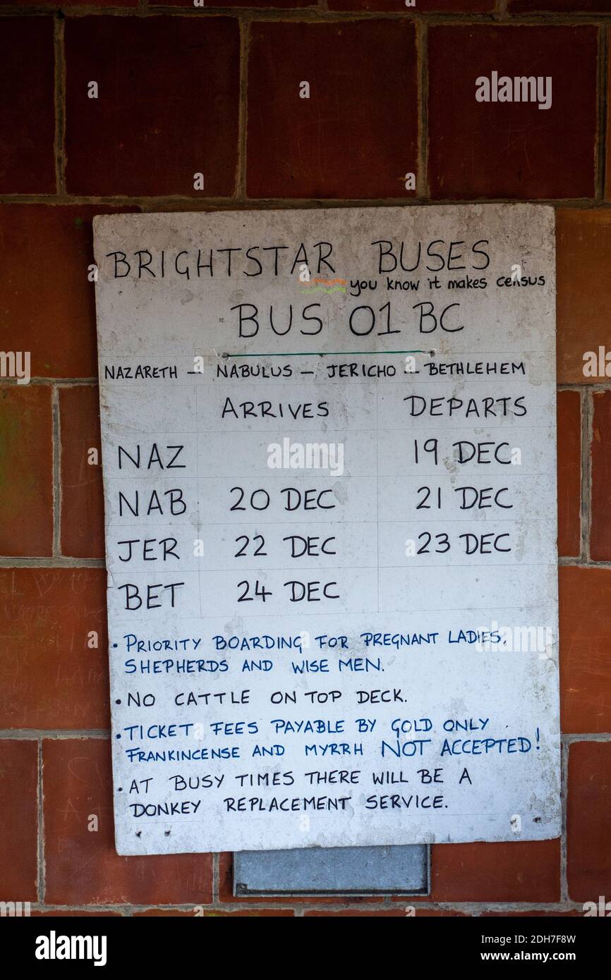 Presepio natalizio in un villaggio di rifugio autobus, Castle Ashby, Northamptonshire, Regno Unito; con un orario di autobus umoristico. Foto Stock