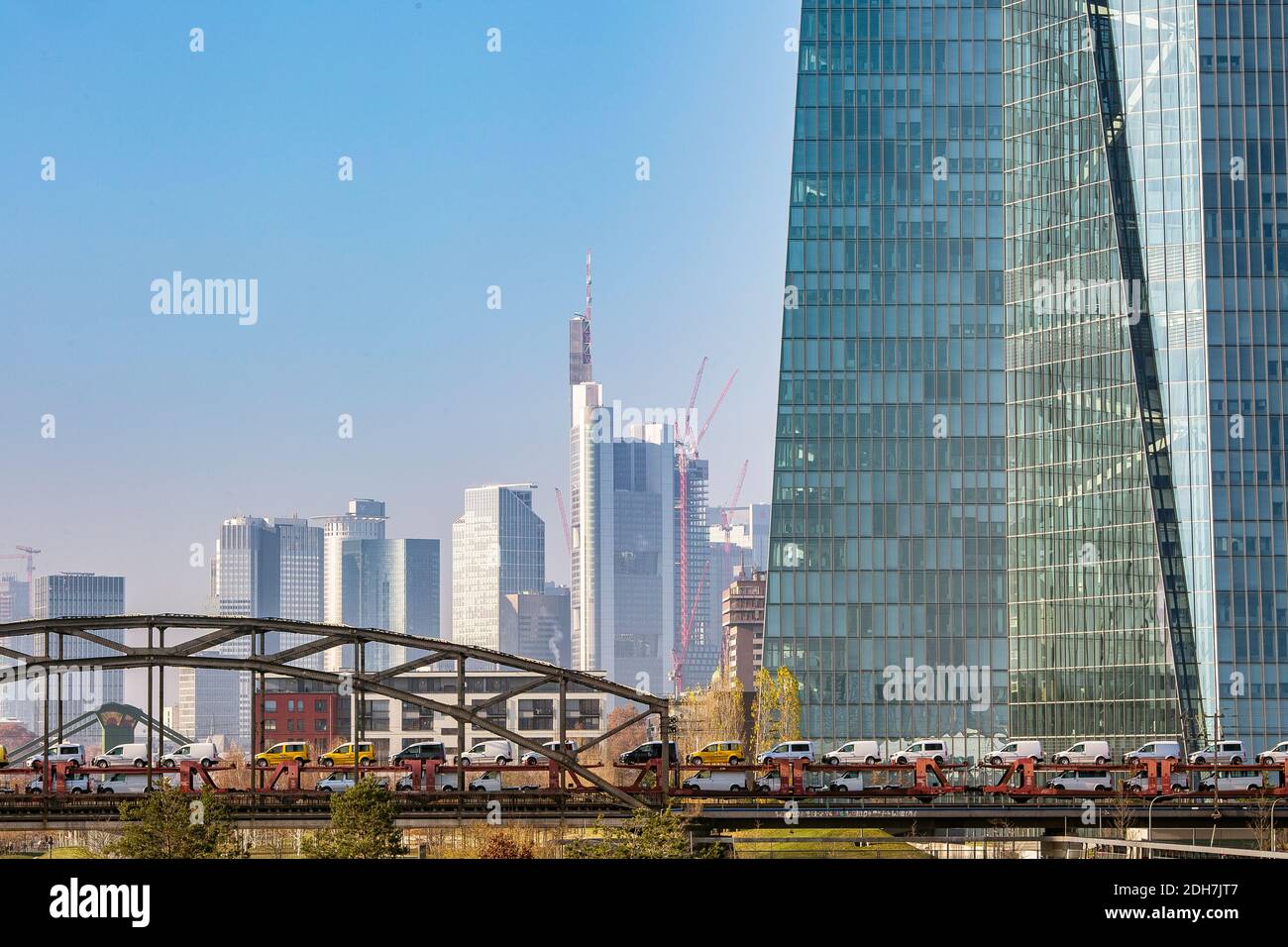Treno merci che trasporta molte automobili che attraversano il ponte ferroviario con lo Skyline di Francoforte sullo sfondo a Francoforte sul meno, Assia, Germania. Foto Stock