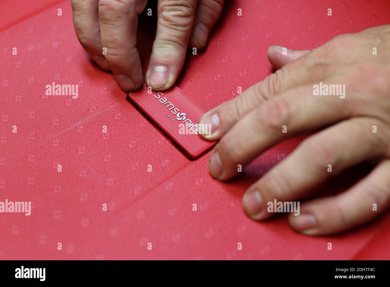 Closeup delle mani dei lavoratori che mettono l'etichetta sulla valigia in una linea di produzione di Samsonite a Oudenaarde, Belgio. Foto Stock