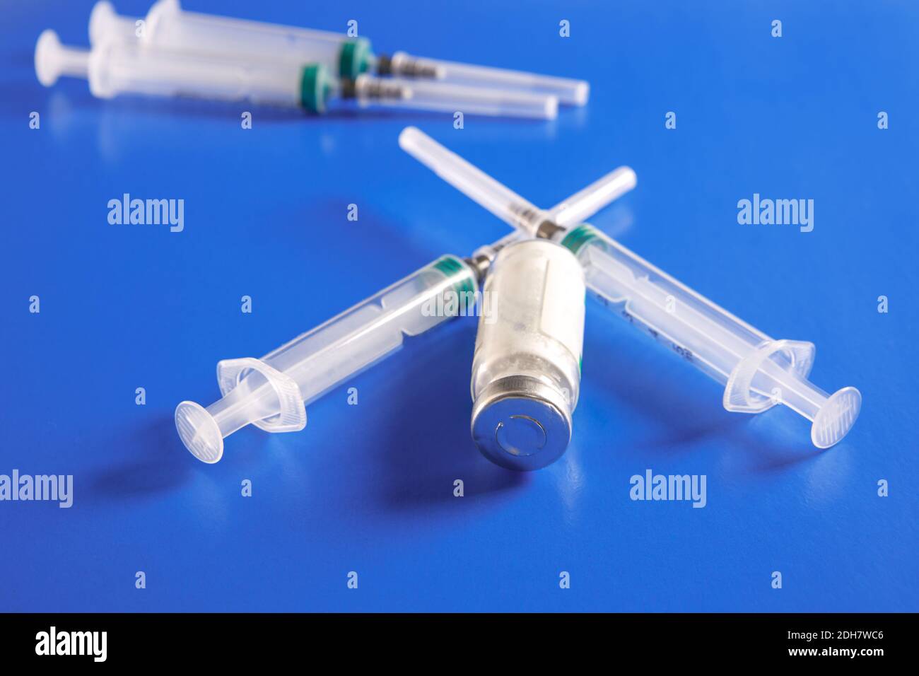 Una fiala con un vaccino e una siringa sono su sfondo blu. Il concetto di vaccinazione contro il coronavirus. Foto Stock