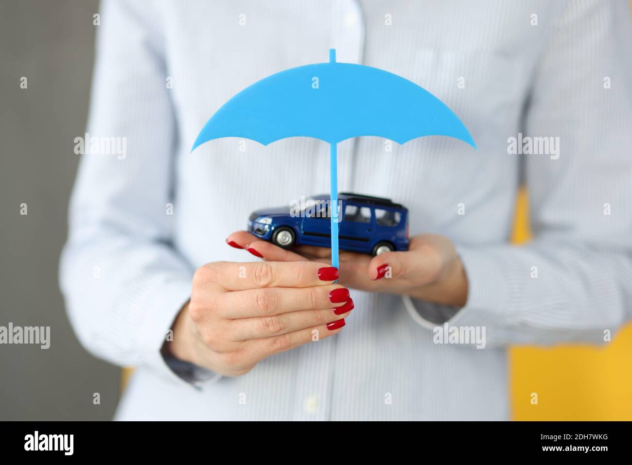 Le mani femminili tengono l'automobile giocattolo e l'ombrello vicino Foto Stock