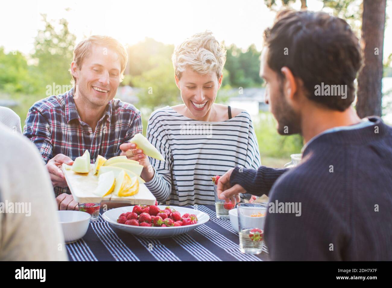 Amici felici che pranzano al tavolo da picnic Foto Stock