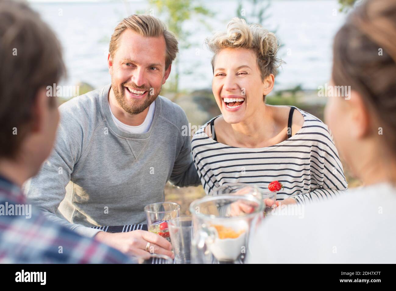 Felici amici che si divertano durante il pranzo al tavolo da picnic Foto Stock