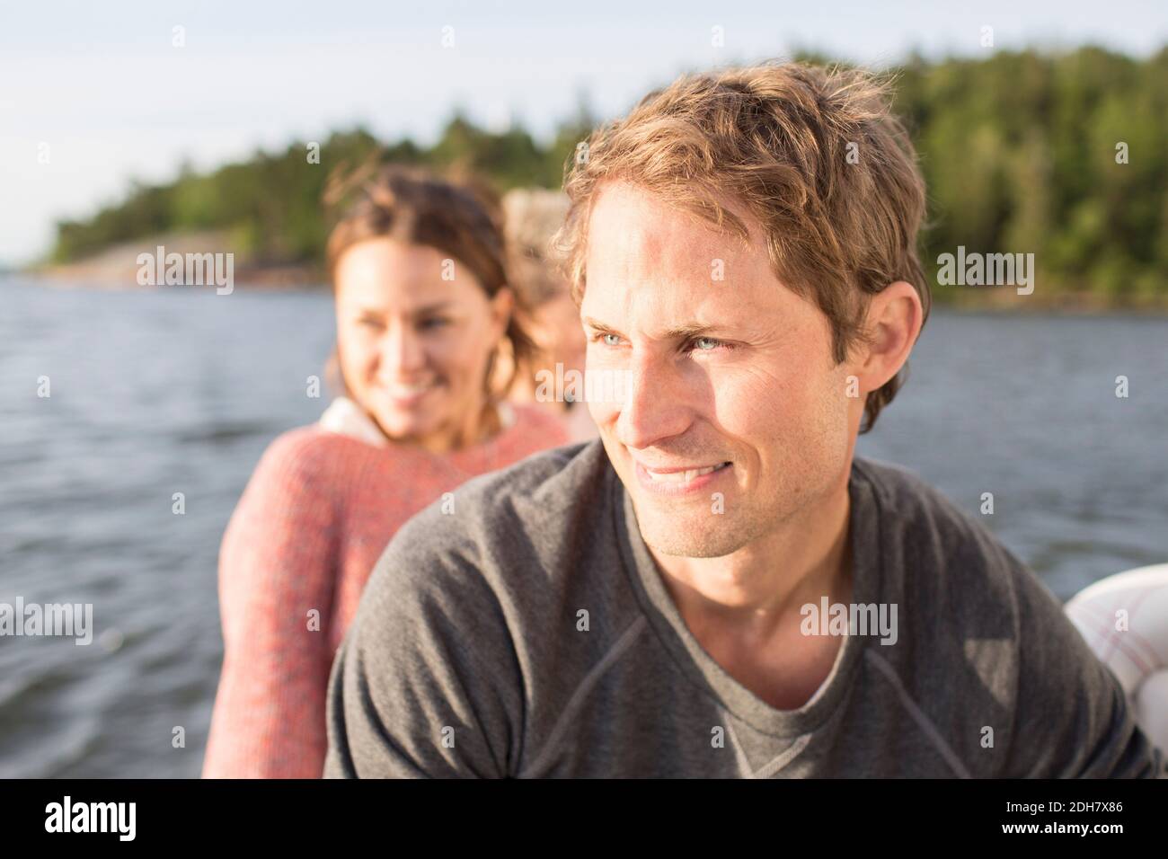 Sorridendo gli amici che guardano via mentre si viaggia in yacht sul fiume Foto Stock