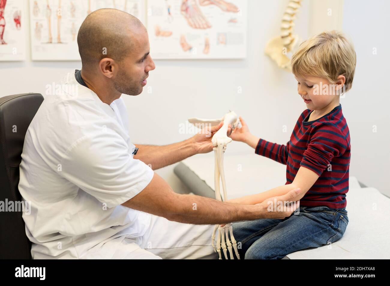 Medico di sesso maschile che spiega il modello di mano al ragazzo presso la clinica ortopedica Foto Stock