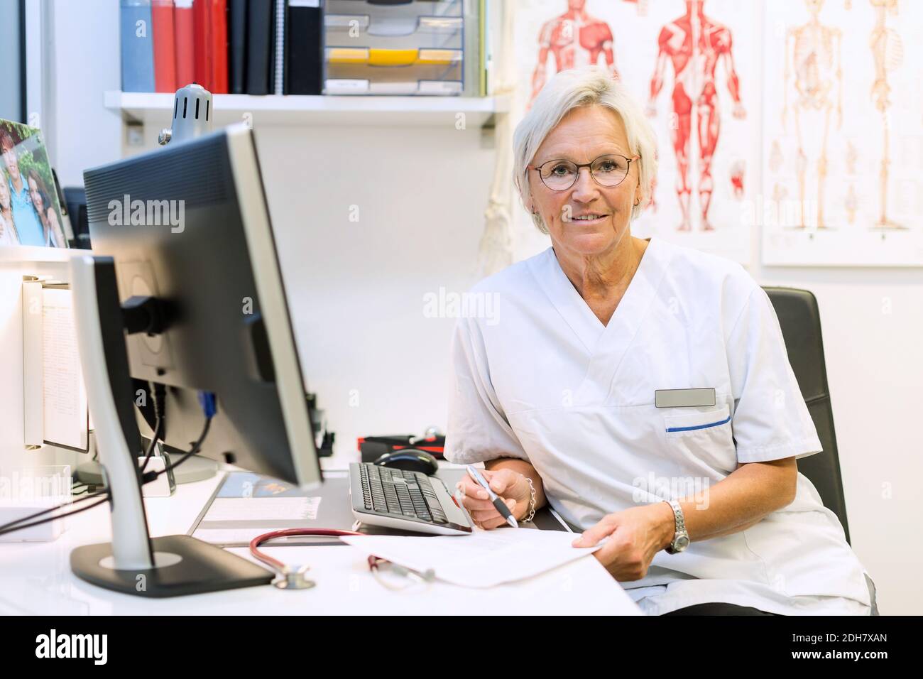 Ritratto di sicuro chirurgo ortopedico seduto alla scrivania del computer dentro clinica Foto Stock
