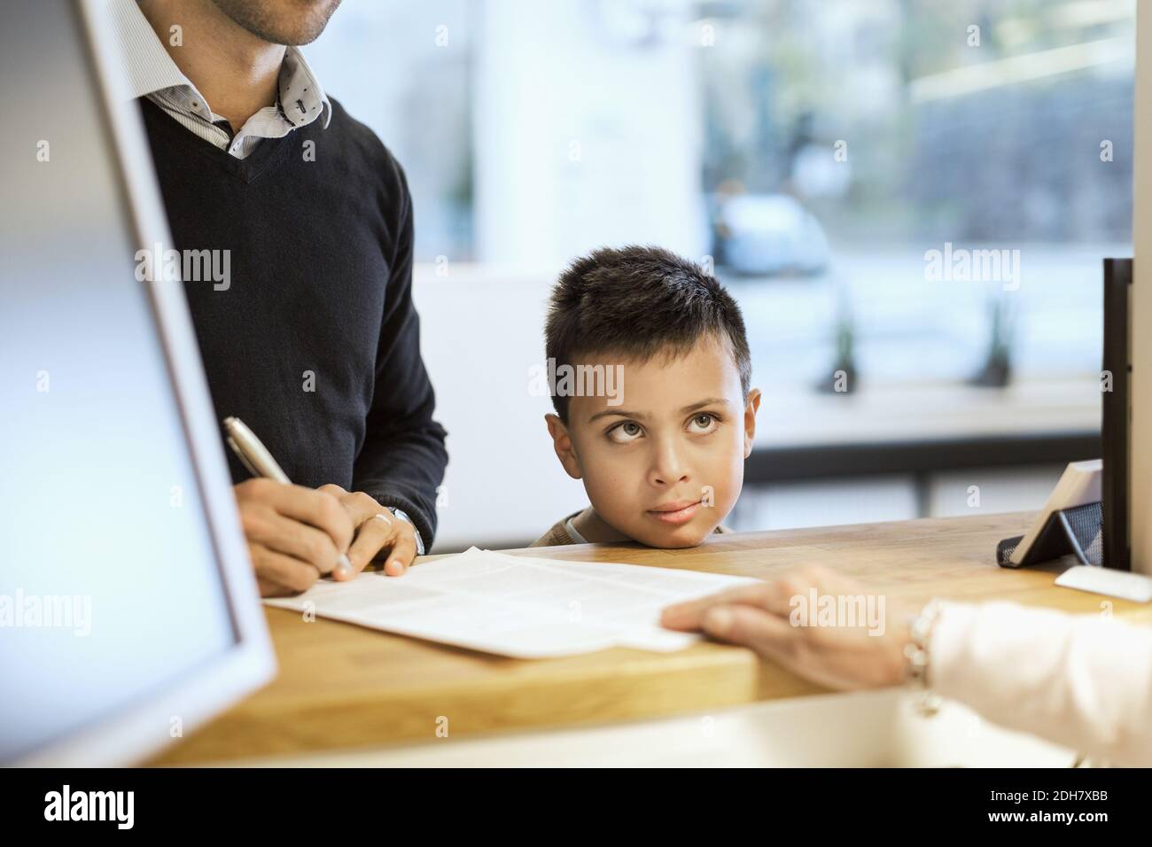 Documenti di riempimento per famiglie al banco della reception in clinica ortopedica Foto Stock