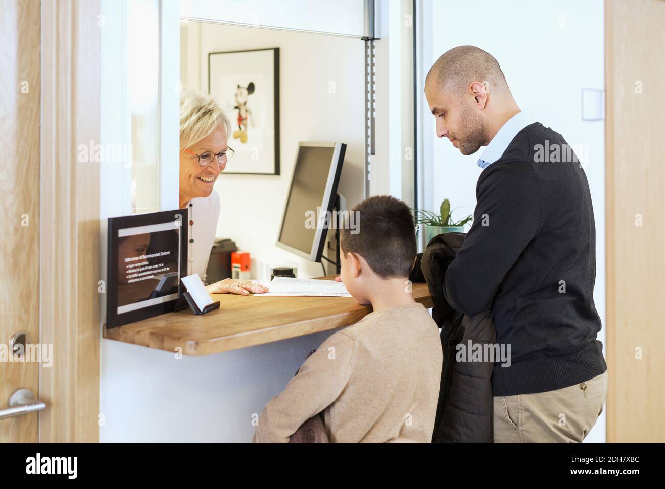 Donna addetta al ricevimento che fornisce documenti medici alla famiglia in ortopedia clinica Foto Stock