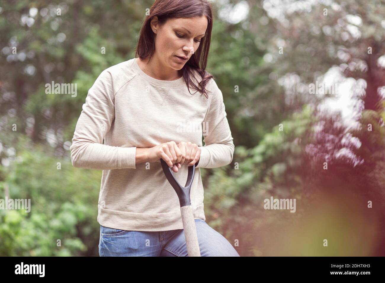 Donna mid adulta che tiene forchetta da giardinaggio in azienda agricola biologica Foto Stock