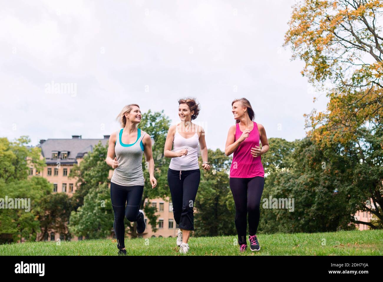 Un'intera lunghezza di donne che fanno jogging al parco contro il cielo Foto Stock