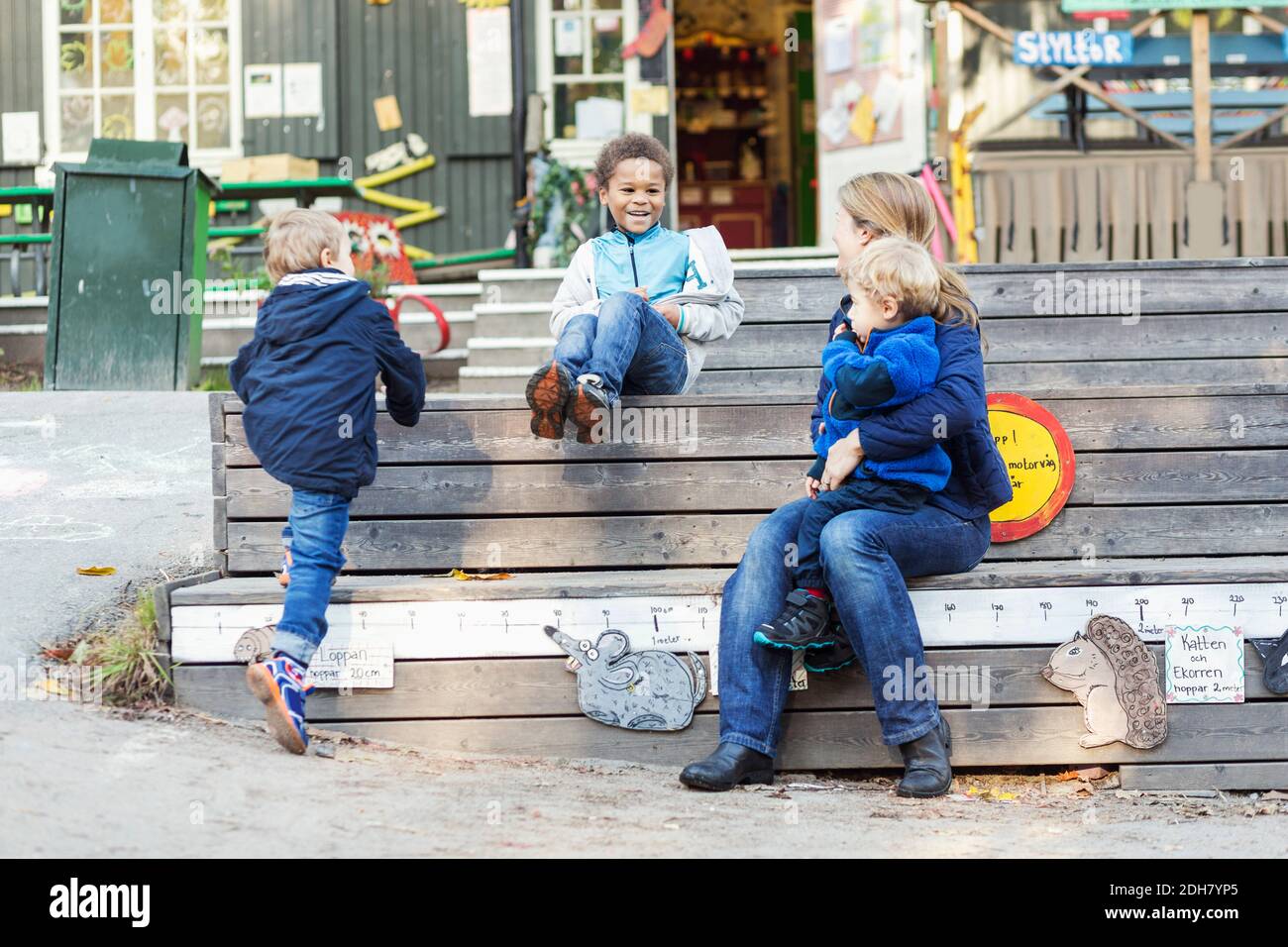 Insegnante e bambini all'esterno dell'edificio prescolare Foto Stock
