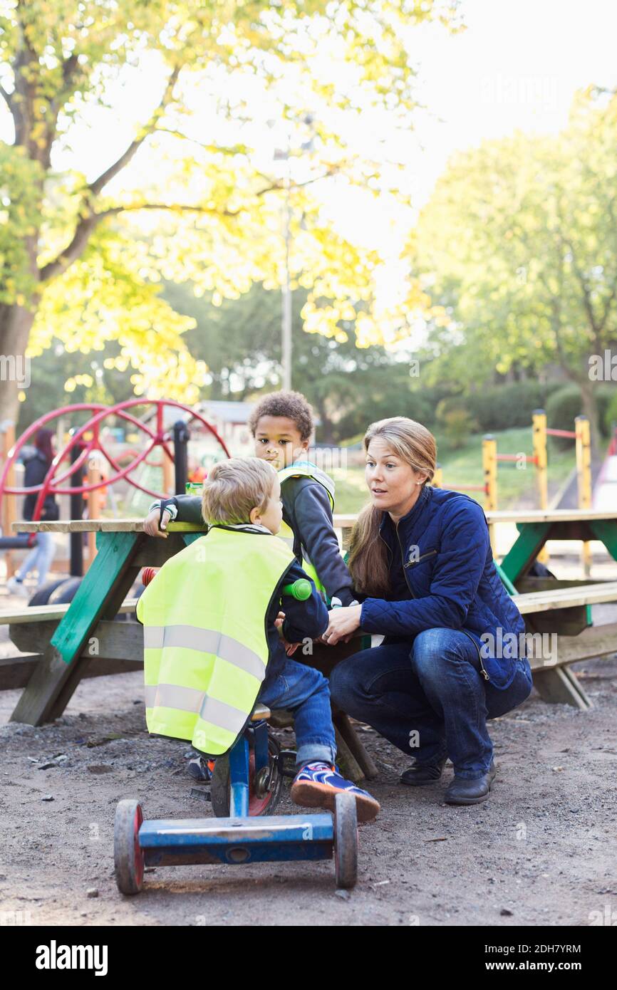 Insegnante di asilo che comunica con lo studente sul parco giochi Foto Stock