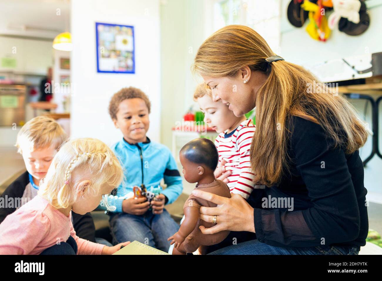 Insegnante e bambini con giocattoli in asilo Foto Stock