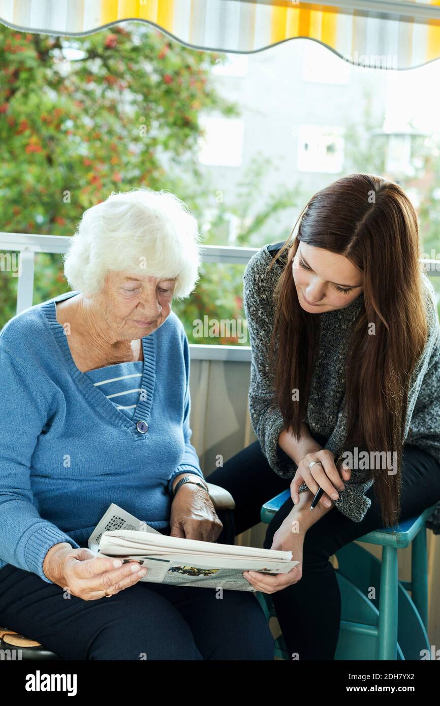 Nonna e nipote che leggono il giornale sul portico Foto Stock