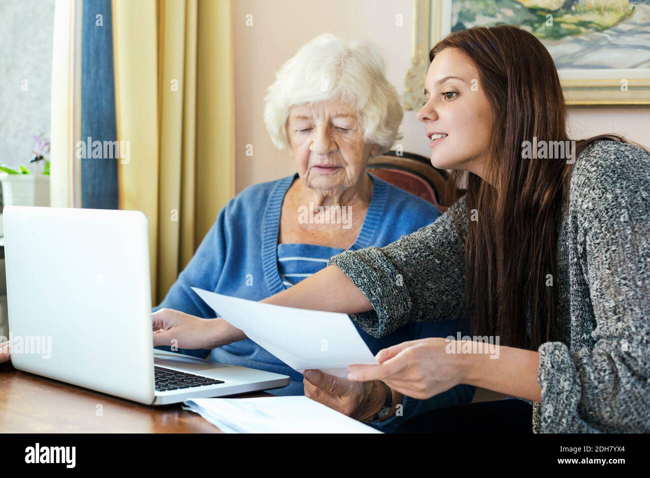 Nonna e nipote con documenti che usano il laptop a casa Foto Stock