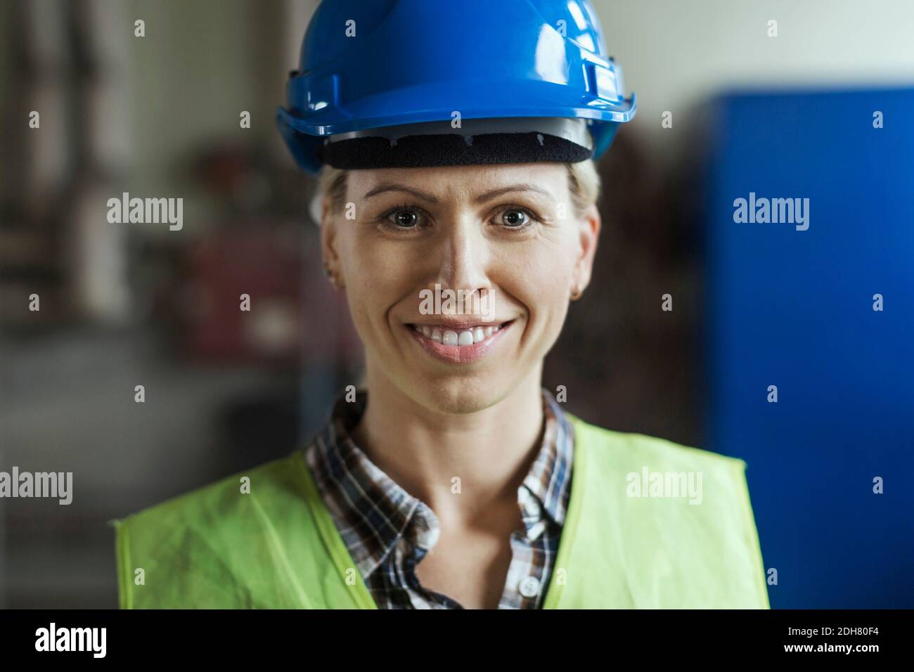 Ritratto di lavoratrice manuale che indossa il cappello in fabbrica Foto Stock