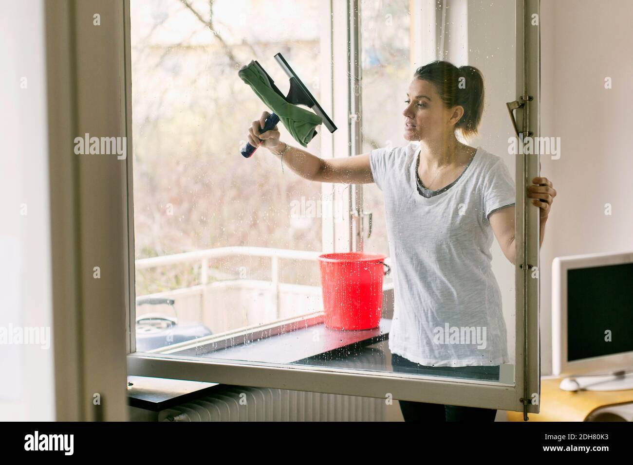 Donna pulizia vetro finestra Foto Stock