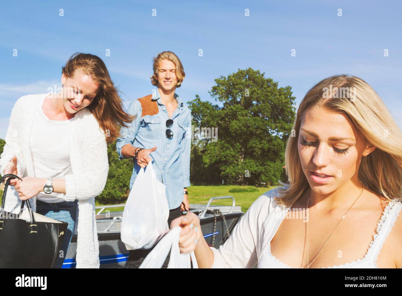 Amici felici che caricano le borse in barca contro il cielo Foto Stock