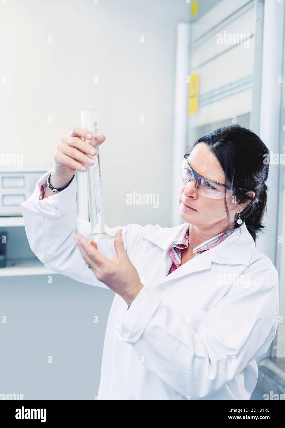 Scienziato femminile che esamina la sostanza chimica in becher in laboratorio Foto Stock