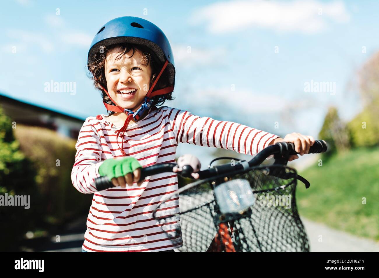 Ragazzo felice che guarda via mentre si sta con la bicicletta sul sentiero in cantiere Foto Stock