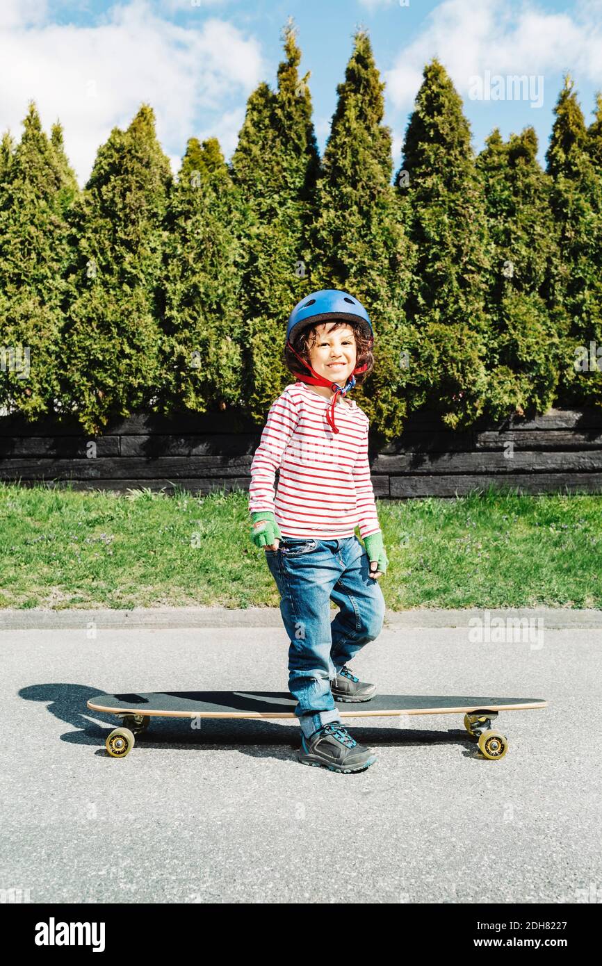 Ritratto di ragazzo sicuro in piedi con skateboard sul sentiero a. iarda Foto Stock