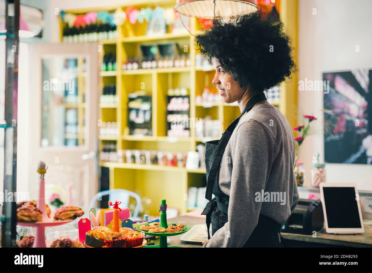 Vista laterale del barista femminile in piedi al banco del caffè Foto Stock