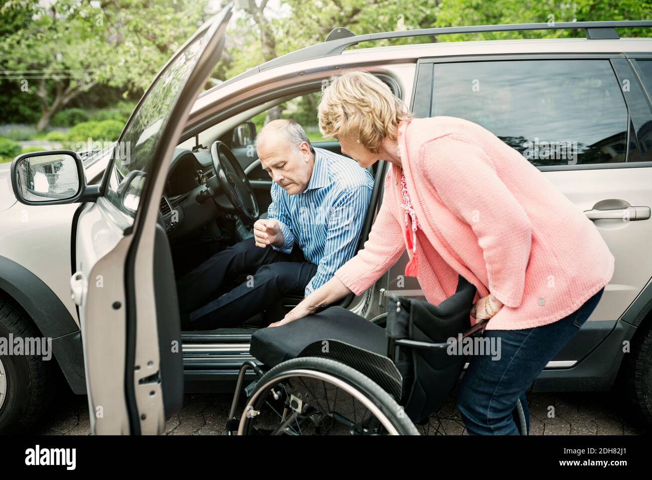 Donna che assiste l'uomo disabile nello sbarco dall'auto Foto Stock
