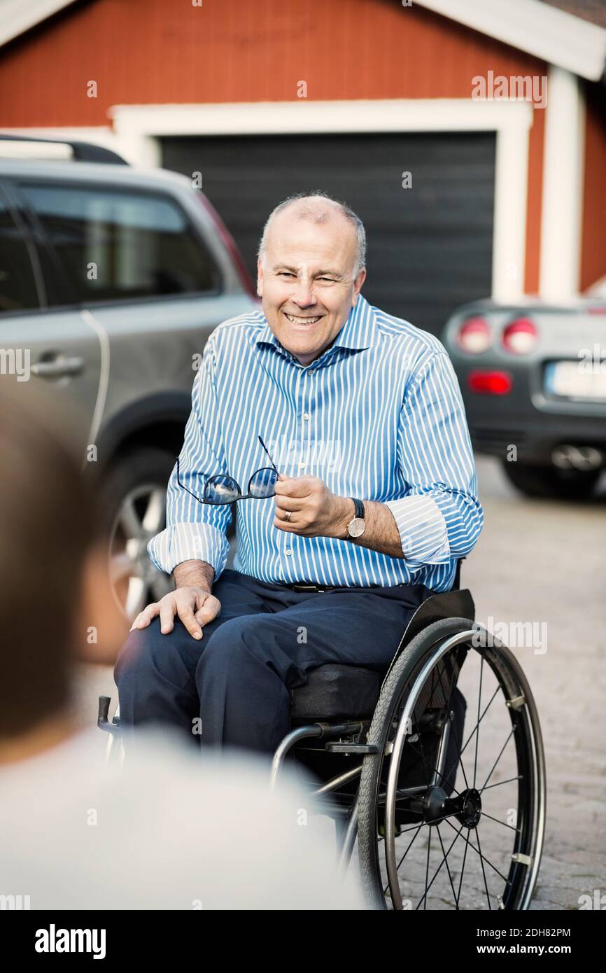 Felice padre in sedia a rotelle che guarda il figlio sulla strada Foto Stock