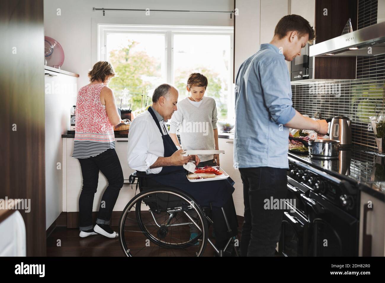 Genitori e bambini preparano insieme il cibo in cucina Foto Stock