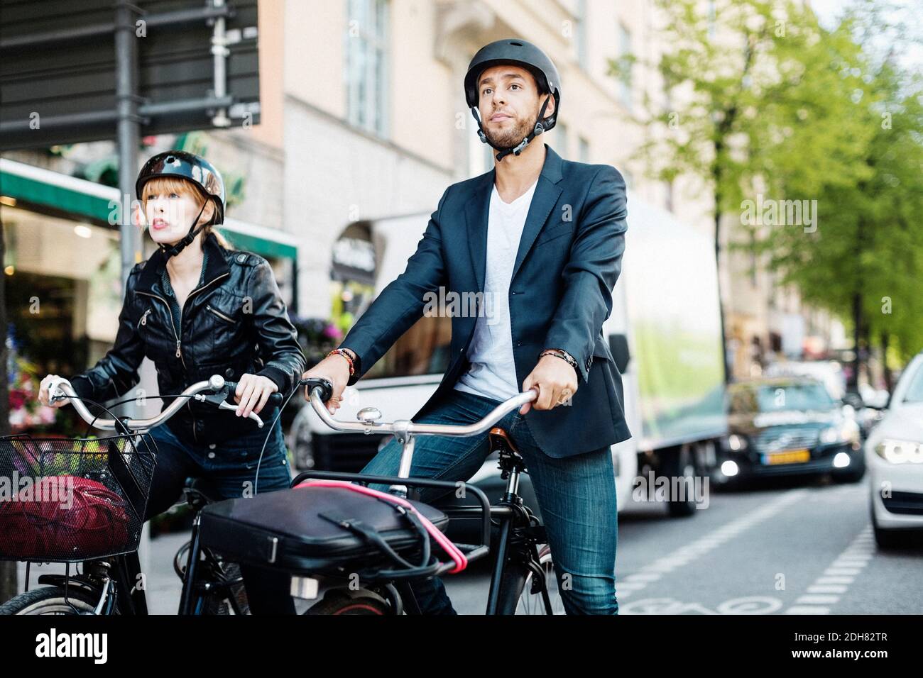 Uomini d'affari in bicicletta che aspettano alla traversata della zebra in città Foto Stock