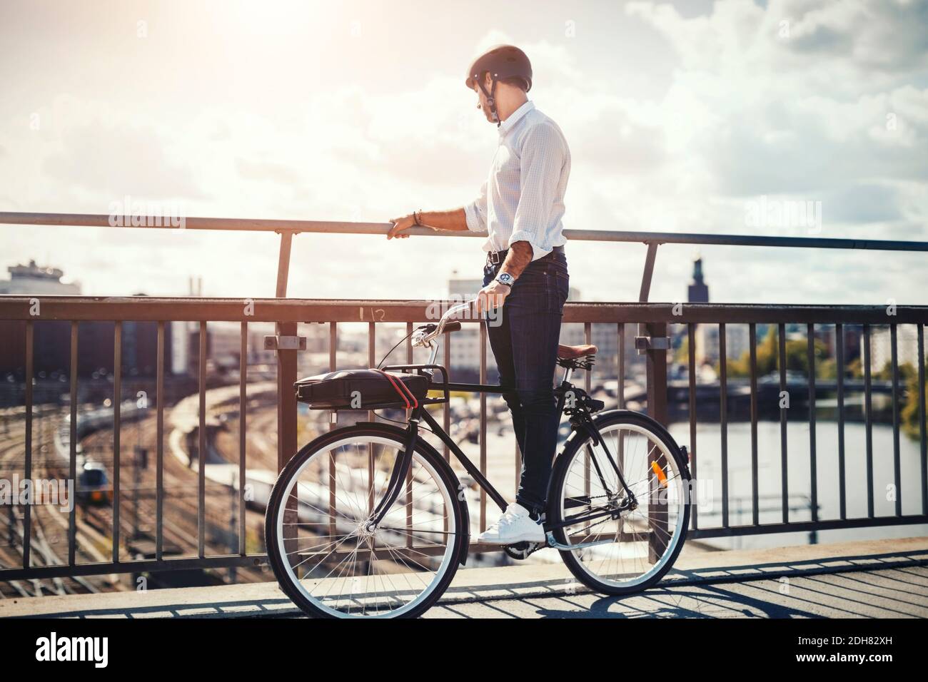 Uomo d'affari che guarda la città mentre si è in piedi in bicicletta Foto Stock