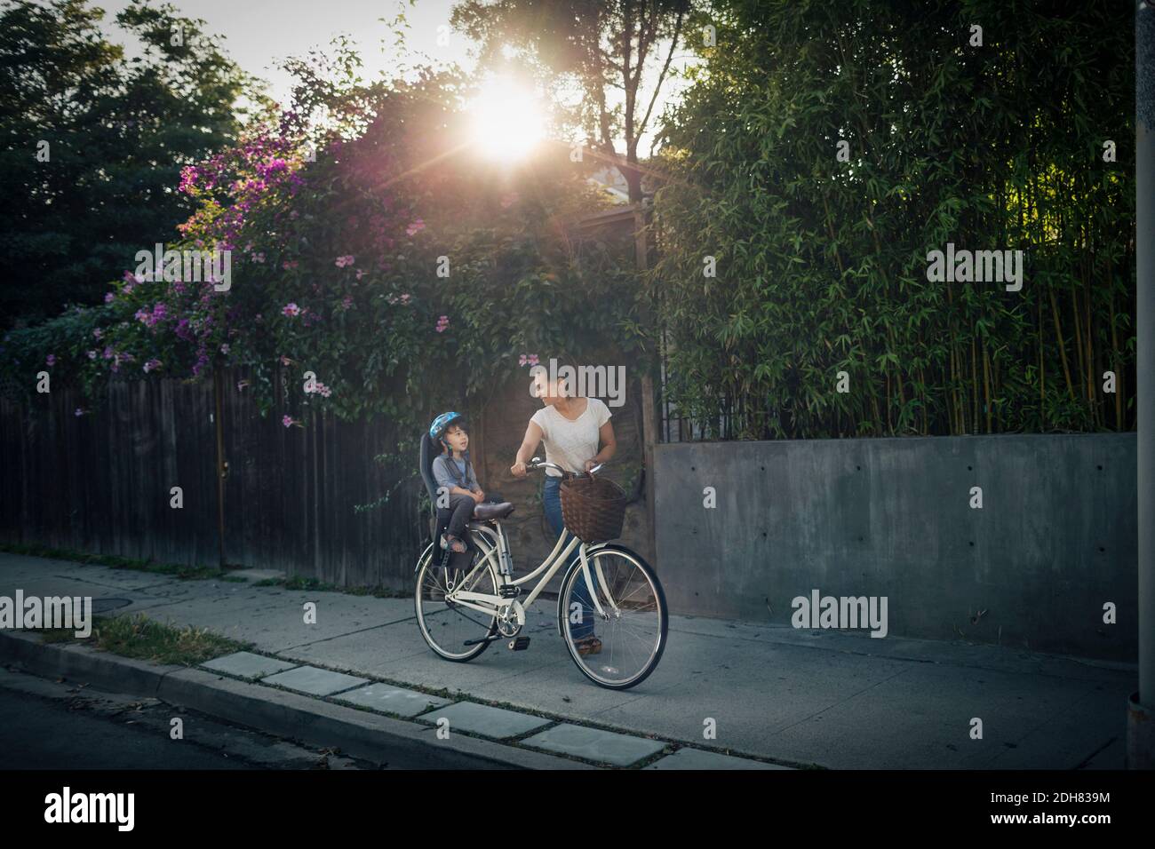 Donna che guarda il figlio seduto sul sedile posteriore della bicicletta all'aperto Foto Stock