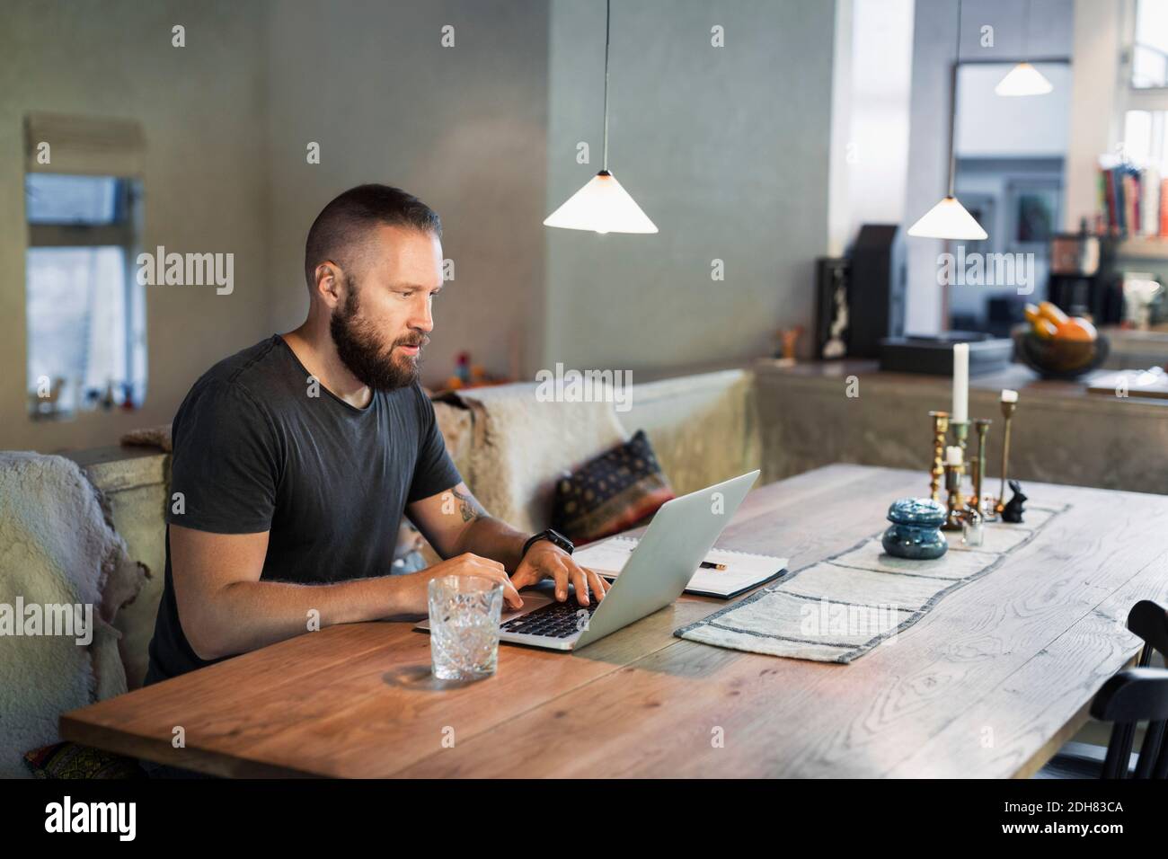 Uomo che lavora su un computer portatile al tavolo da pranzo in casa Foto Stock