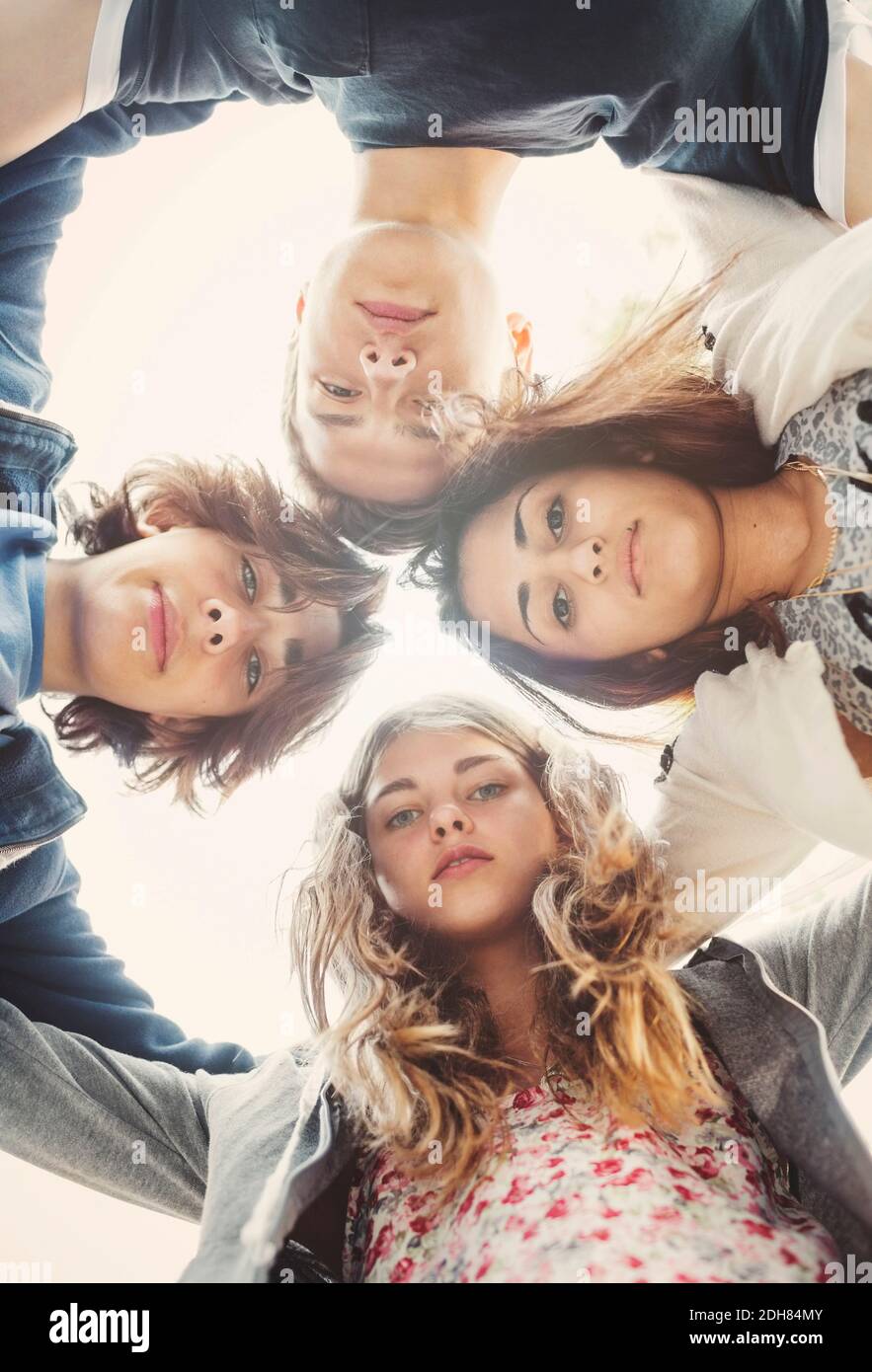 Direttamente sotto ritratto di adolescenti che formano huddle contro il cielo Foto Stock